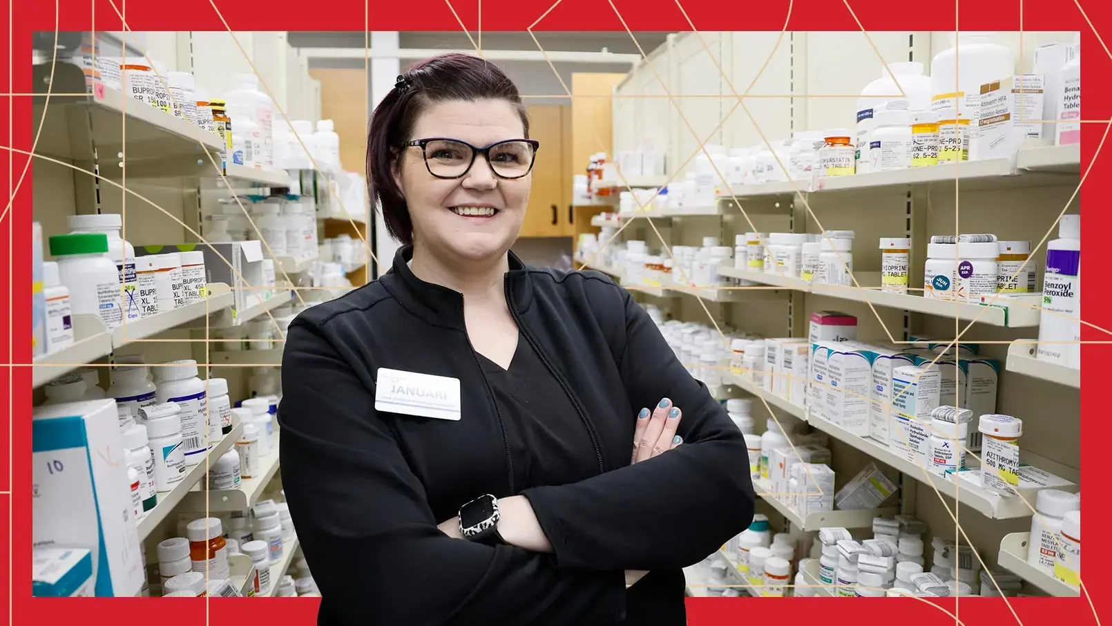 Lead Pharmacy Technician Januari Vaughn poses with her arms crossed among shelves of pill bottles. The photo has a red border and thin, gold, and geometric lines running through the background.