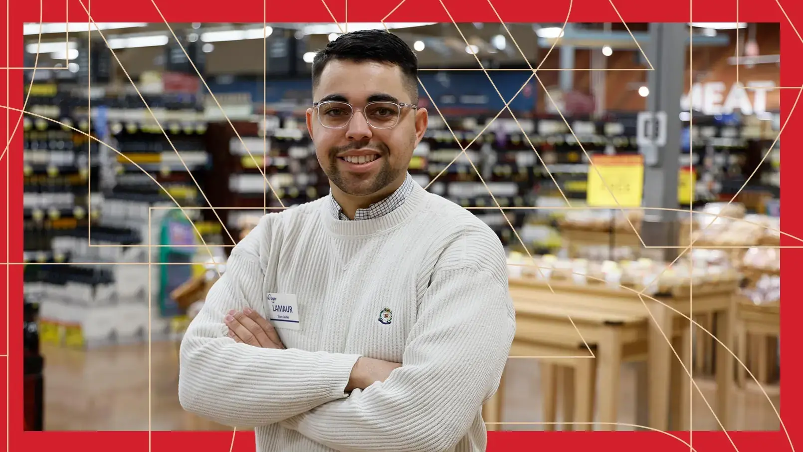 Kroger Store Leader Lamaur Buck proudly poses in front of his grocery store. The photo has a red border and thin, gold, and geometric lines running through the background.